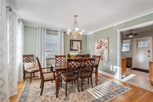 dining area featuring crown molding, baseboards, light wood-type flooring, and a chandelier