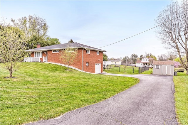 view of side of home featuring driveway, a chimney, brick siding, fence, and an attached garage