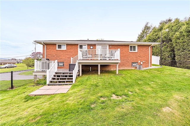 rear view of house with fence, a wooden deck, a yard, and brick siding