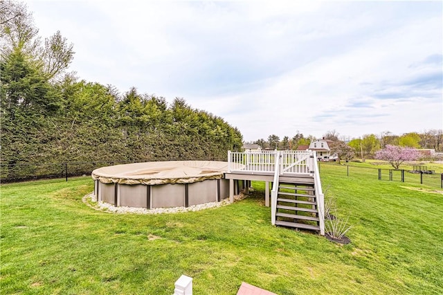 view of yard with stairway, fence, a wooden deck, and a covered pool