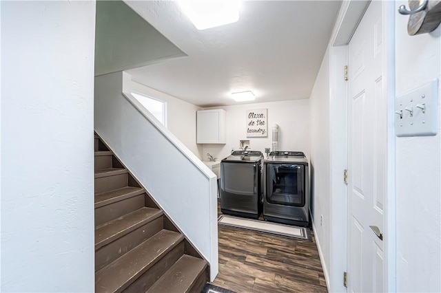 clothes washing area featuring wood finished floors, cabinet space, and washer and dryer