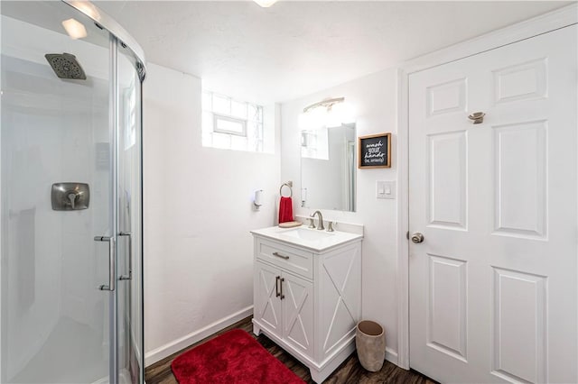 bathroom with baseboards, wood finished floors, a stall shower, and vanity