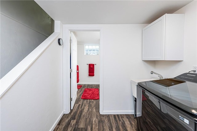 laundry area featuring cabinet space, baseboards, and dark wood-style floors