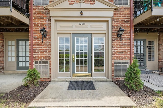 property entrance with brick siding and a balcony
