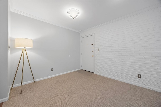 carpeted empty room featuring baseboards, ornamental molding, and brick wall