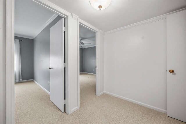 corridor with light colored carpet, baseboards, and crown molding