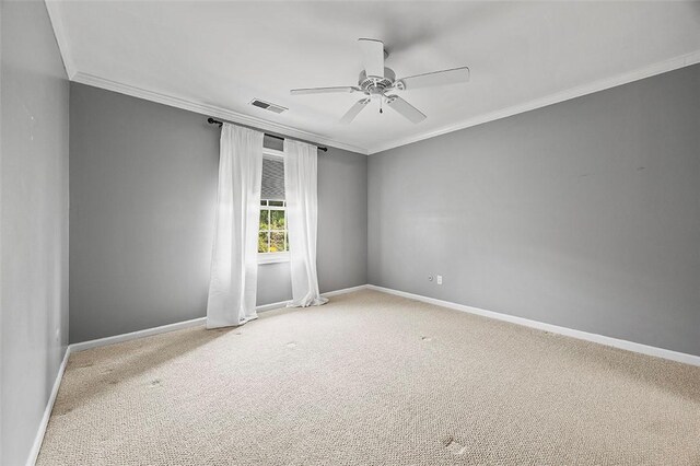carpeted empty room with visible vents, a ceiling fan, baseboards, and ornamental molding