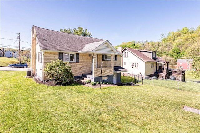 back of property featuring brick siding, roof with shingles, fence, and a lawn
