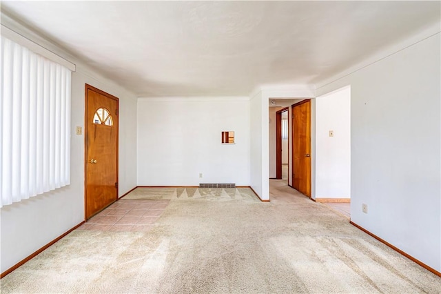 spare room featuring light colored carpet, baseboards, and visible vents