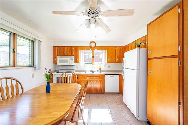 kitchen with brown cabinets, light tile patterned flooring, ceiling fan, a sink, and white appliances