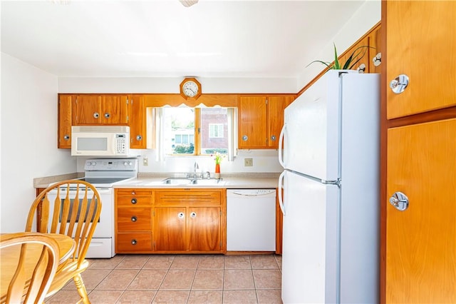 kitchen with a sink, brown cabinets, white appliances, and light countertops