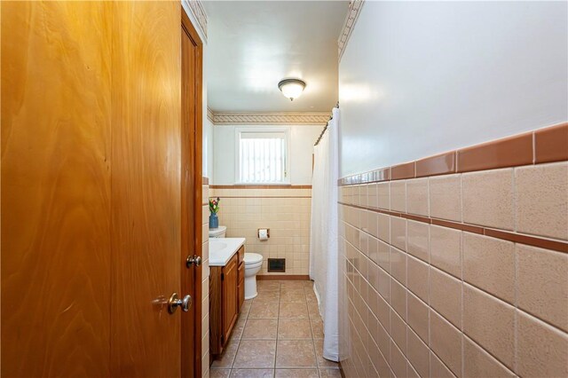 full bathroom featuring tile patterned flooring, vanity, visible vents, toilet, and tile walls