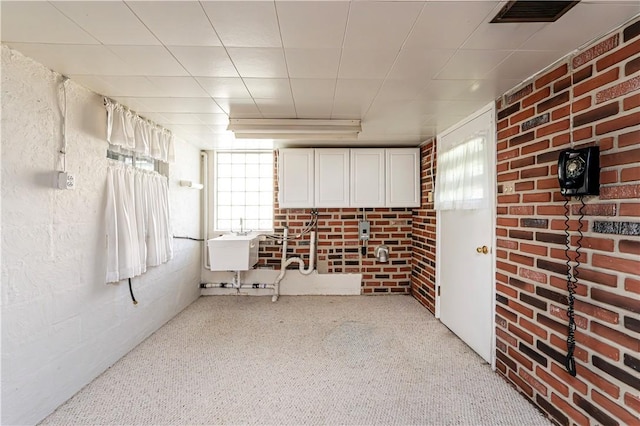 below grade area featuring carpet floors, brick wall, and visible vents
