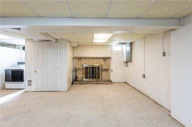 basement featuring carpet, a drop ceiling, electric panel, and a fireplace