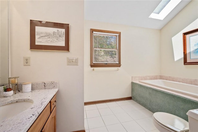 bathroom featuring a garden tub, vanity, toilet, baseboards, and a skylight