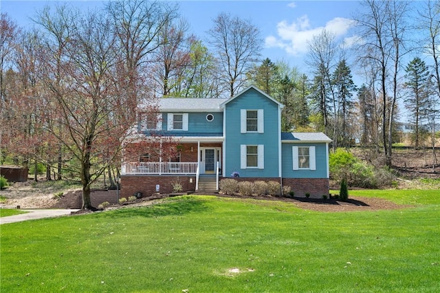 traditional home featuring covered porch, brick siding, and a front yard