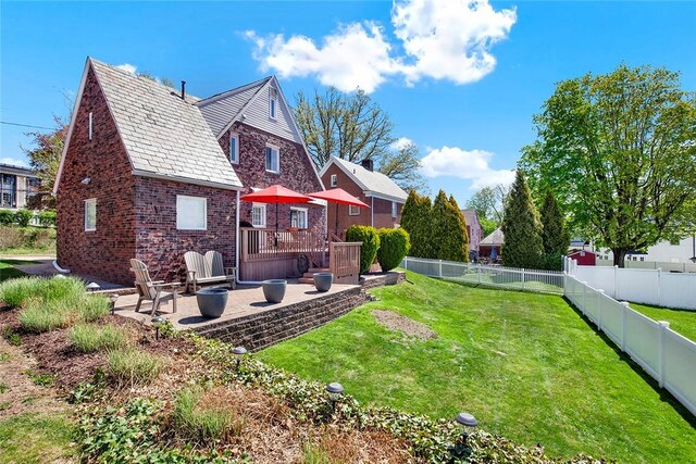 rear view of property with a high end roof, a patio area, brick siding, a fenced backyard, and a yard