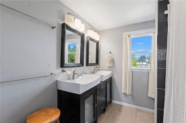full bath featuring double vanity, tile patterned floors, a wealth of natural light, and a sink
