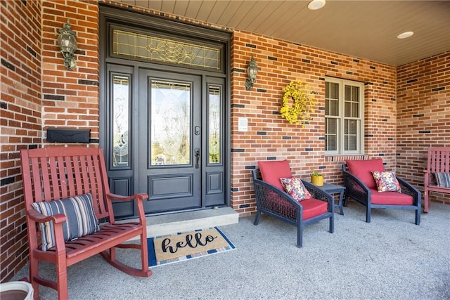 view of exterior entry featuring brick siding and a porch