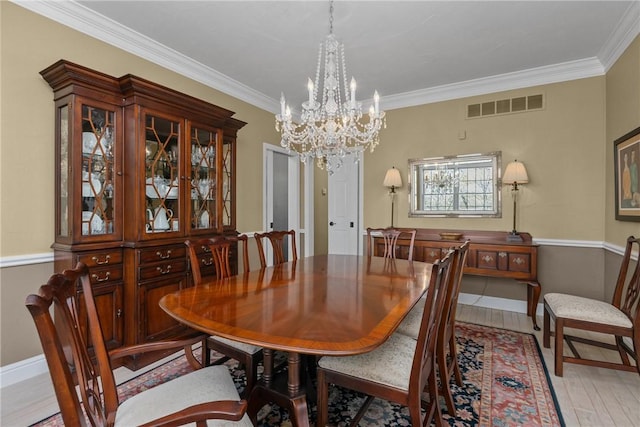 dining room with visible vents, crown molding, baseboards, light wood-type flooring, and a notable chandelier