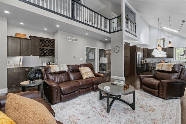 living area with bar, visible vents, high vaulted ceiling, baseboards, and recessed lighting