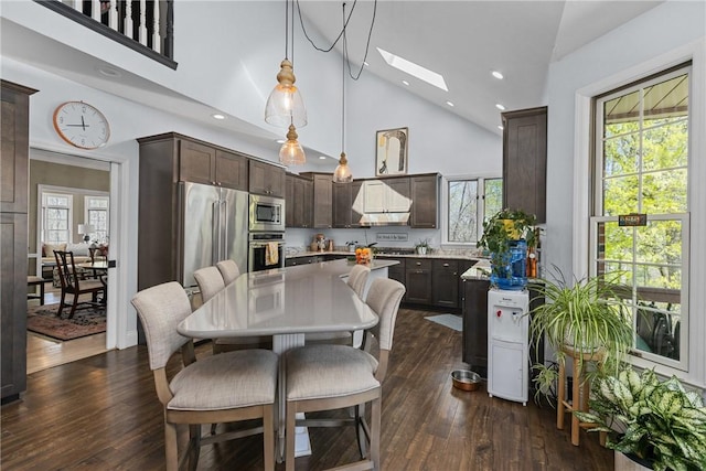 dining space featuring dark wood-style flooring, a skylight, recessed lighting, and high vaulted ceiling
