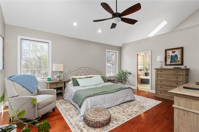 bedroom with vaulted ceiling with skylight, recessed lighting, a ceiling fan, ensuite bathroom, and dark wood-type flooring
