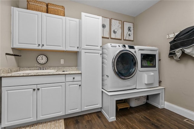 washroom featuring washing machine and clothes dryer, a sink, dark wood-type flooring, and cabinet space