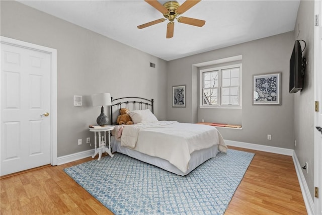 bedroom featuring baseboards, a ceiling fan, wood finished floors, and visible vents