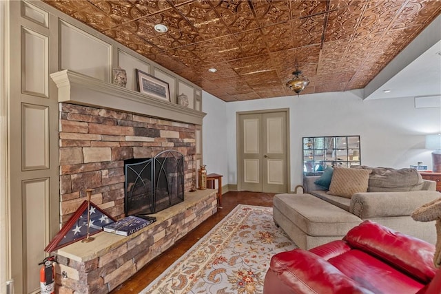 living room with a stone fireplace, an ornate ceiling, and wood finished floors