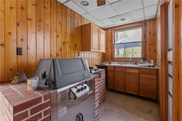 kitchen featuring a sink, wood walls, brown cabinets, and light countertops