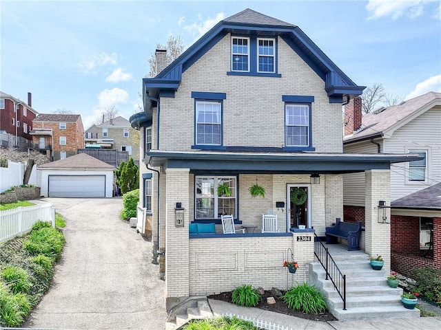 traditional style home with covered porch, a chimney, an outbuilding, a garage, and brick siding
