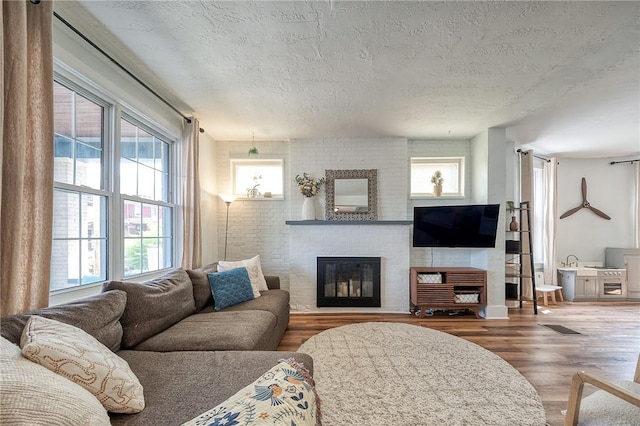 living room with visible vents, a textured ceiling, wood finished floors, and a fireplace