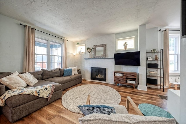 living room with a textured ceiling, a fireplace, wood finished floors, and visible vents