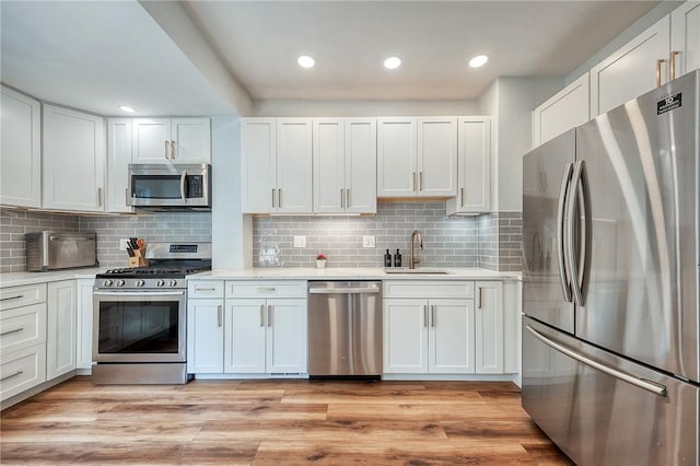 kitchen featuring recessed lighting, light countertops, white cabinetry, a sink, and appliances with stainless steel finishes