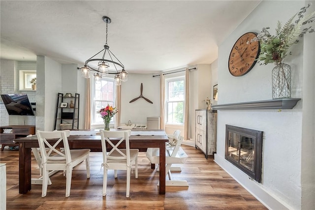 dining room with baseboards, a glass covered fireplace, a wealth of natural light, and wood finished floors
