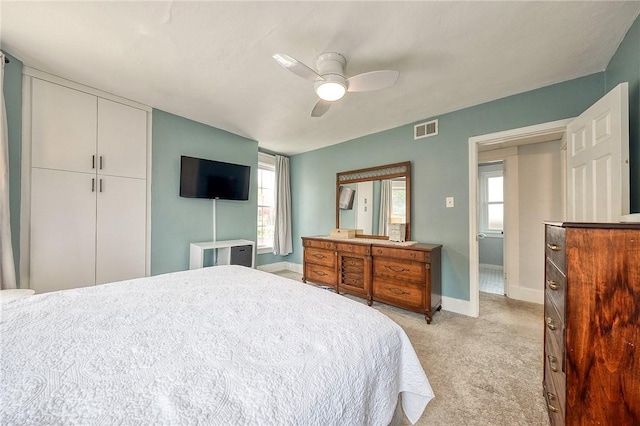 bedroom with baseboards, light carpet, a ceiling fan, and visible vents