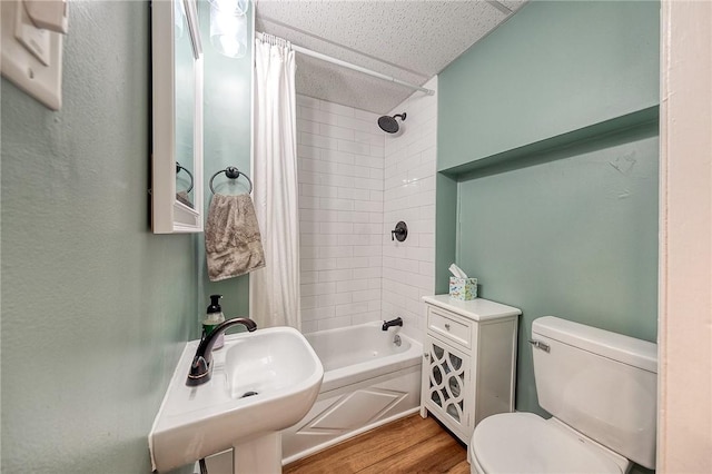 bathroom featuring a sink, shower / bath combo with shower curtain, toilet, and wood finished floors