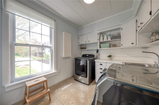 washroom with a sink, independent washer and dryer, cabinet space, and a healthy amount of sunlight