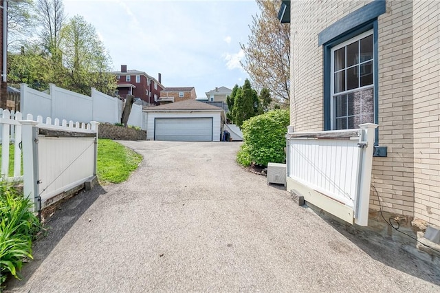 view of side of property with a detached garage, fence, and brick siding