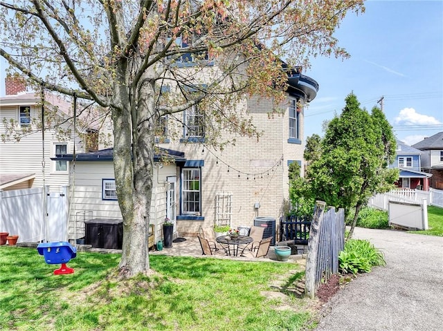 back of property with a yard, fence, and a gate