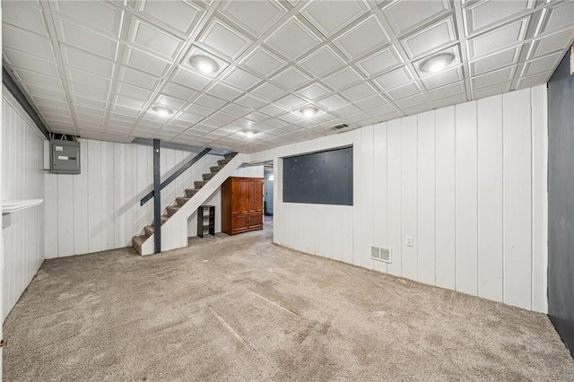 finished below grade area featuring visible vents, carpet, stairs, and wooden walls