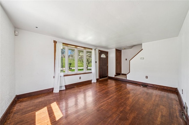 unfurnished living room featuring baseboards, stairs, and wood finished floors