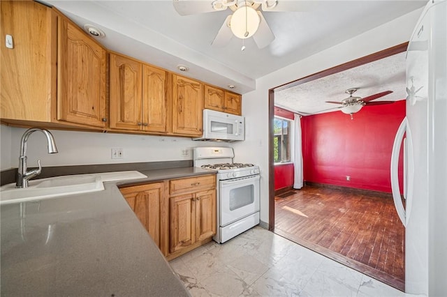 kitchen featuring a ceiling fan, a sink, baseboards, marble finish floor, and white appliances