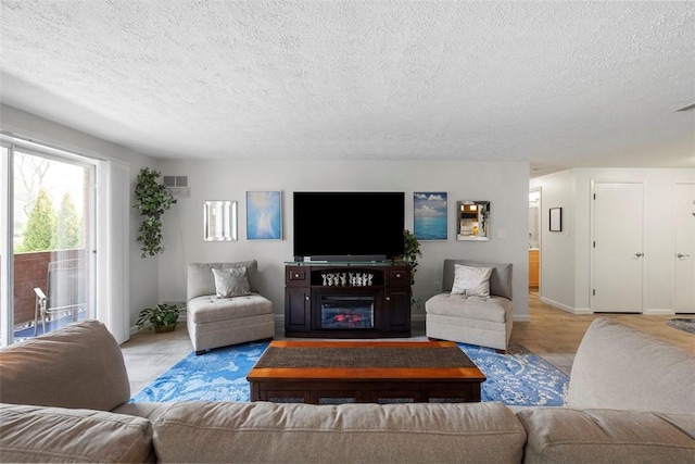living area featuring baseboards, a textured ceiling, and visible vents