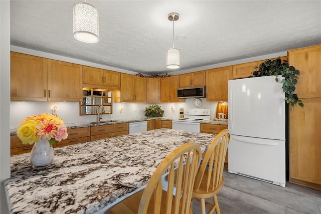 kitchen featuring a textured ceiling, pendant lighting, light stone countertops, a sink, and white appliances