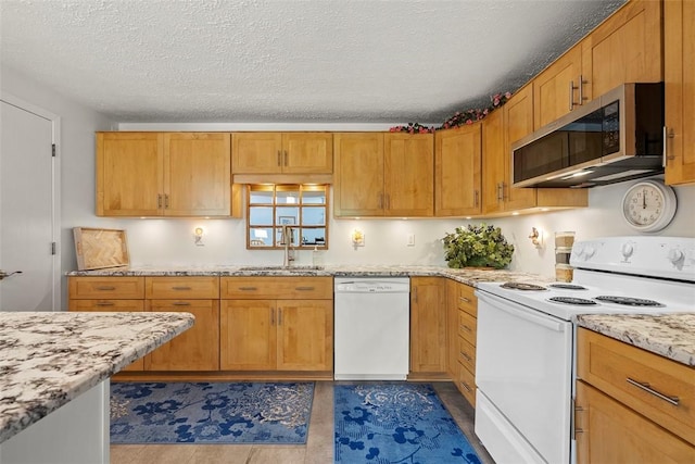 kitchen featuring white appliances, light stone countertops, a textured ceiling, brown cabinets, and a sink