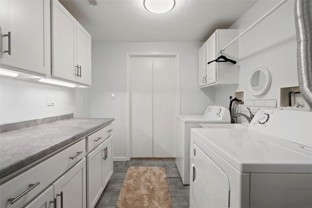 washroom featuring a textured ceiling, cabinet space, and independent washer and dryer