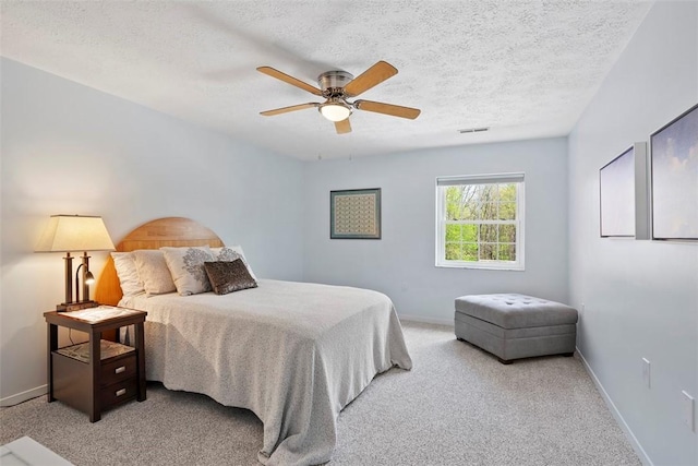 bedroom with a textured ceiling, light colored carpet, ceiling fan, and visible vents