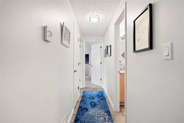 corridor featuring a textured ceiling and baseboards